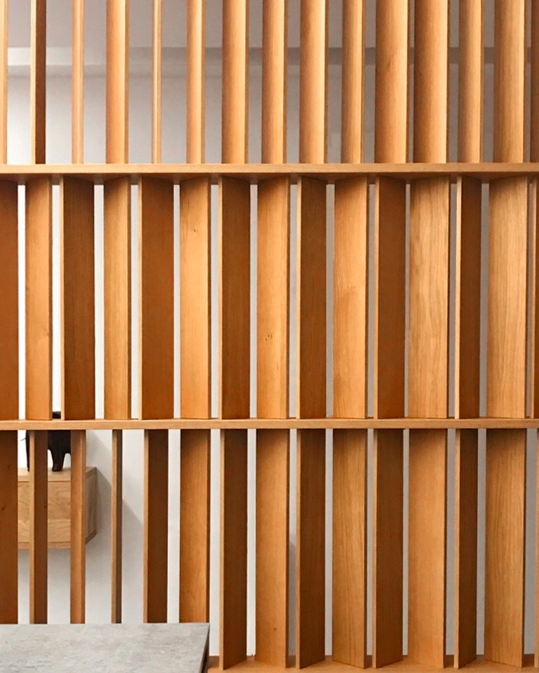 Close view of a vertical timber screen filtering light and views within the renovated interior.