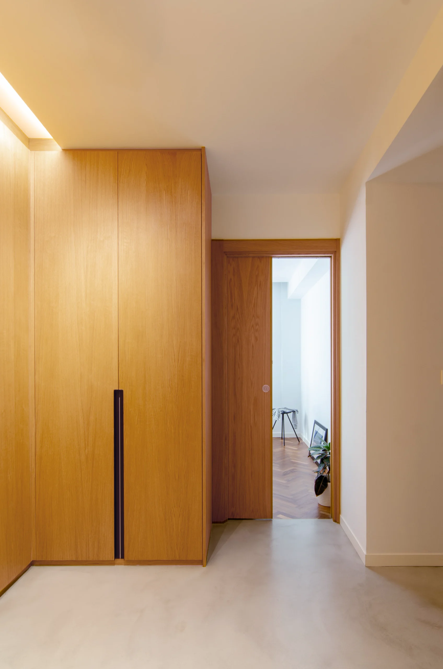 Interior passage lined with full-height timber storage and softly illuminated by concealed indirect lighting.