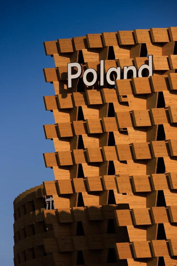 Close view of the Poland sign mounted on the pavilion’s projecting Japanese pine façade modules.